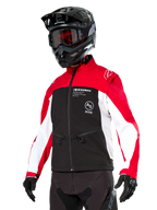 Chaqueta Softshell Alpinestars Lite-Dura, chaqueta de moto, negro, rojo brillante y blanco, vestida por un piloto con casco de motocross negro, gafas rojas y guantes, con logotipos llamativos en el pecho, diseñada para conducción off-road y enduro