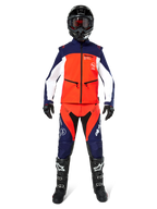 Piloto de motocross con equipamiento completo de off-road, Chaqueta Softshell Lite-Dura en azul marino, naranja intenso y blanco, pantalones a juego en azul marino y naranja, casco negro con gafas, botas negras y blancas, guantes negros, conjunto coordinado para carreras de enduro