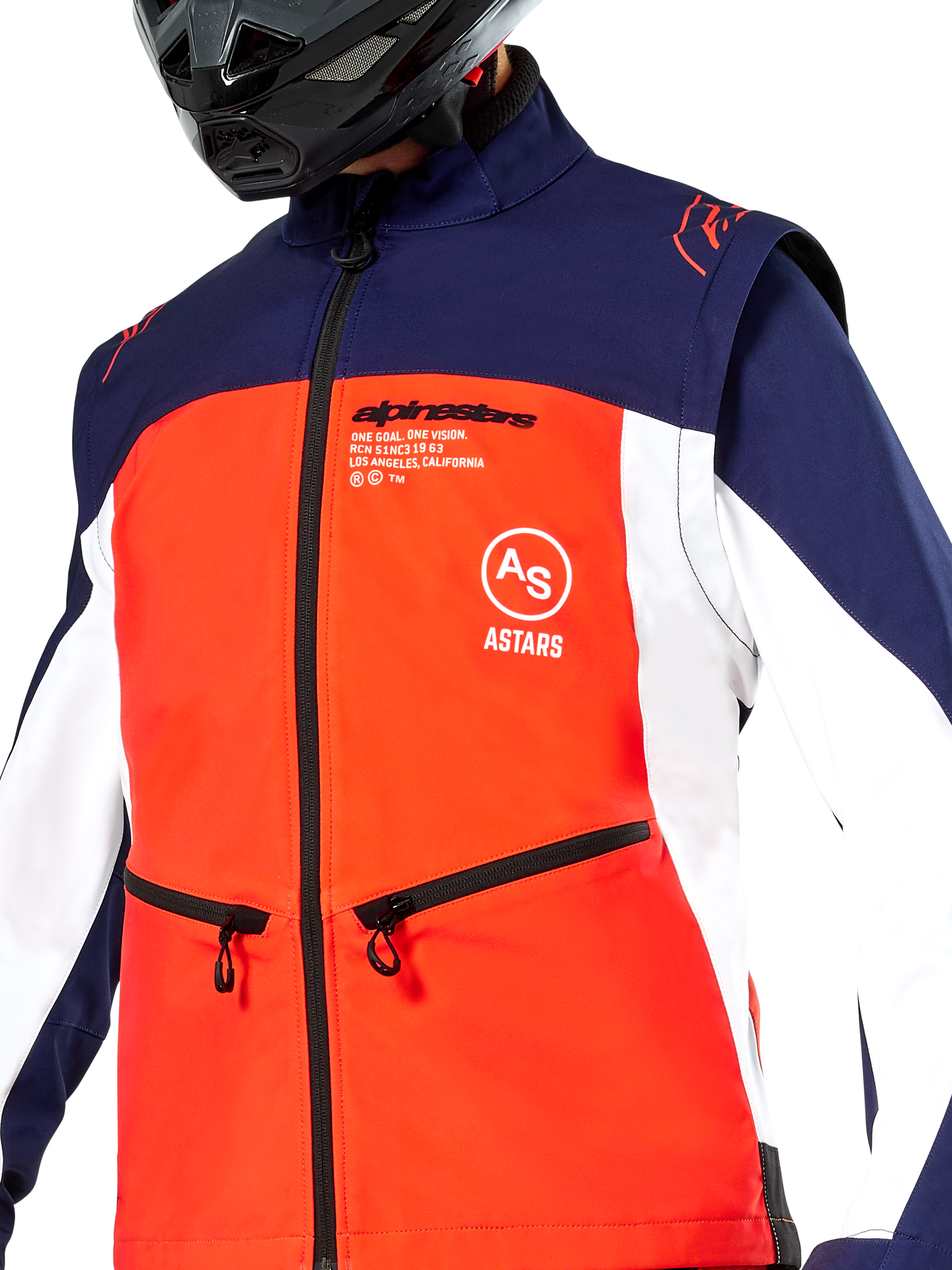 Chaqueta Softshell Alpinestars Lite-Dura en azul marino, naranja vibrante y blanco, vista en primer plano del torso, con un panel frontal naranja brillante, paneles laterales blancos y hombros azul marino, bolsillos para las manos con cremallera y marca Alpinestars destacada, usada por un piloto con un casco negro de off-road.