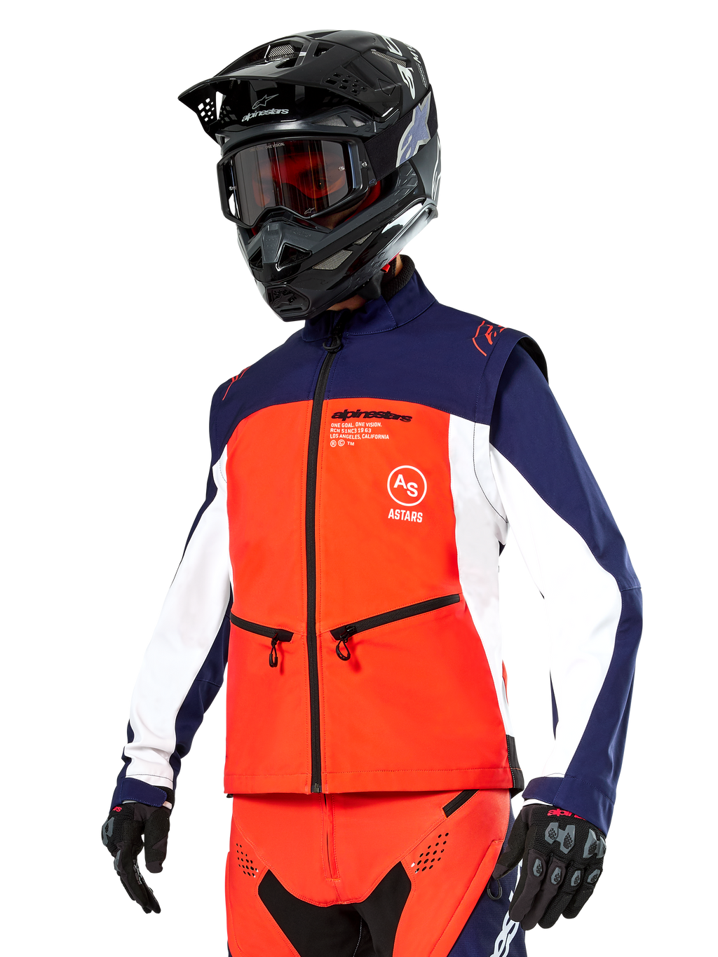 Chaqueta Softshell Alpinestars Lite-Dura en azul marino, naranja intenso y blanco, equipamiento de motocross, combinada con casco y gafas negras, guantes protectores y pantalones de carreras a juego