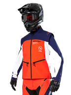 Chaqueta Softshell Alpinestars Lite-Dura en azul marino, naranja intenso y blanco, equipamiento de motocross, combinada con casco y gafas negras, guantes protectores y pantalones de carreras a juego