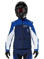 Piloto de motocross con la chaqueta Alpinestars Lite-Dura Softshell en azul marino, azul brillante y blanco, vista frontal, combinada con un casco negro y gafas con lentes rojas, con un diseño técnico cortavientos con bolsillos con cremallera y detalles en blanco para conducción de enduro off-road