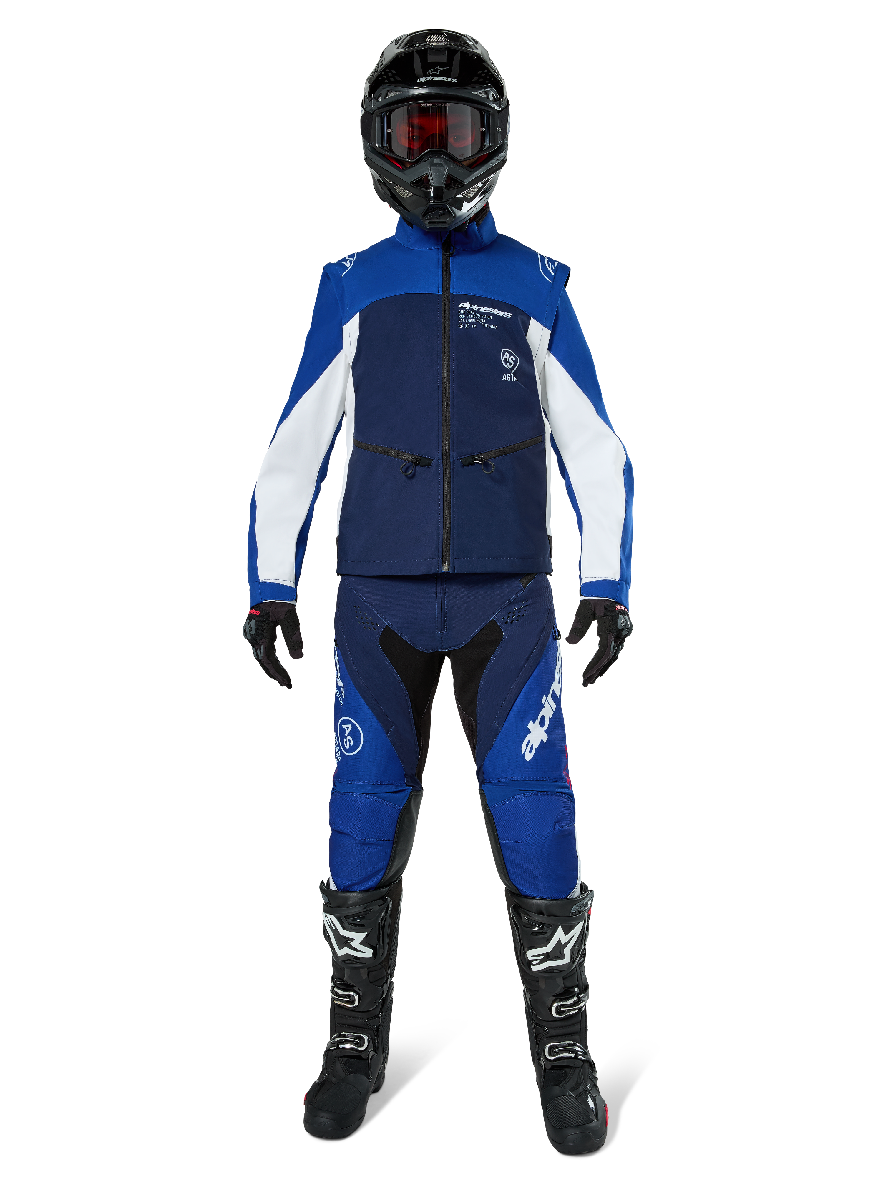 Chaqueta Alpinestars Lite-Dura Softshell, chaqueta de motociclismo off-road en azul marino, azul brillante y blanco, usada con un conjunto de equipamiento completo a juego que incluye casco negro, pantalones de enduro y botas negras, ropa técnica cortavientos para la conducción de motos de cross