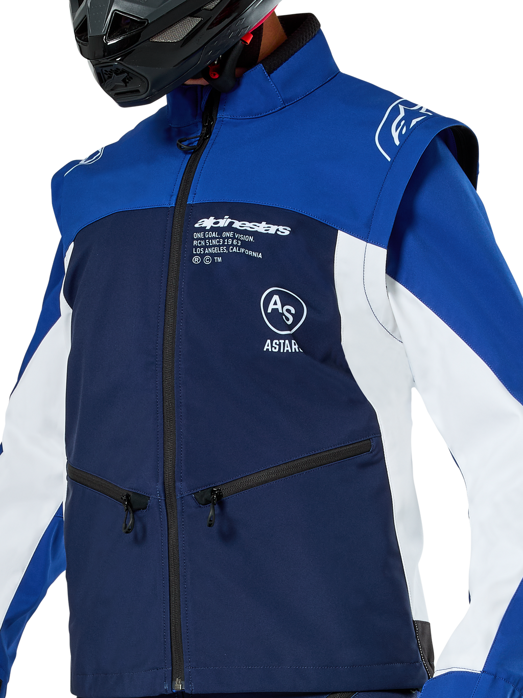 Chaqueta Softshell Alpinestars Lite-Dura, chaqueta de motocross y enduro, azul marino, azul brillante y blanco, con logotipos de Alpinestars en blanco en el pecho y bolsillos con cremallera, usada con un casco negro, construcción de softshell duradera con mangas desmontables para conducción off-road