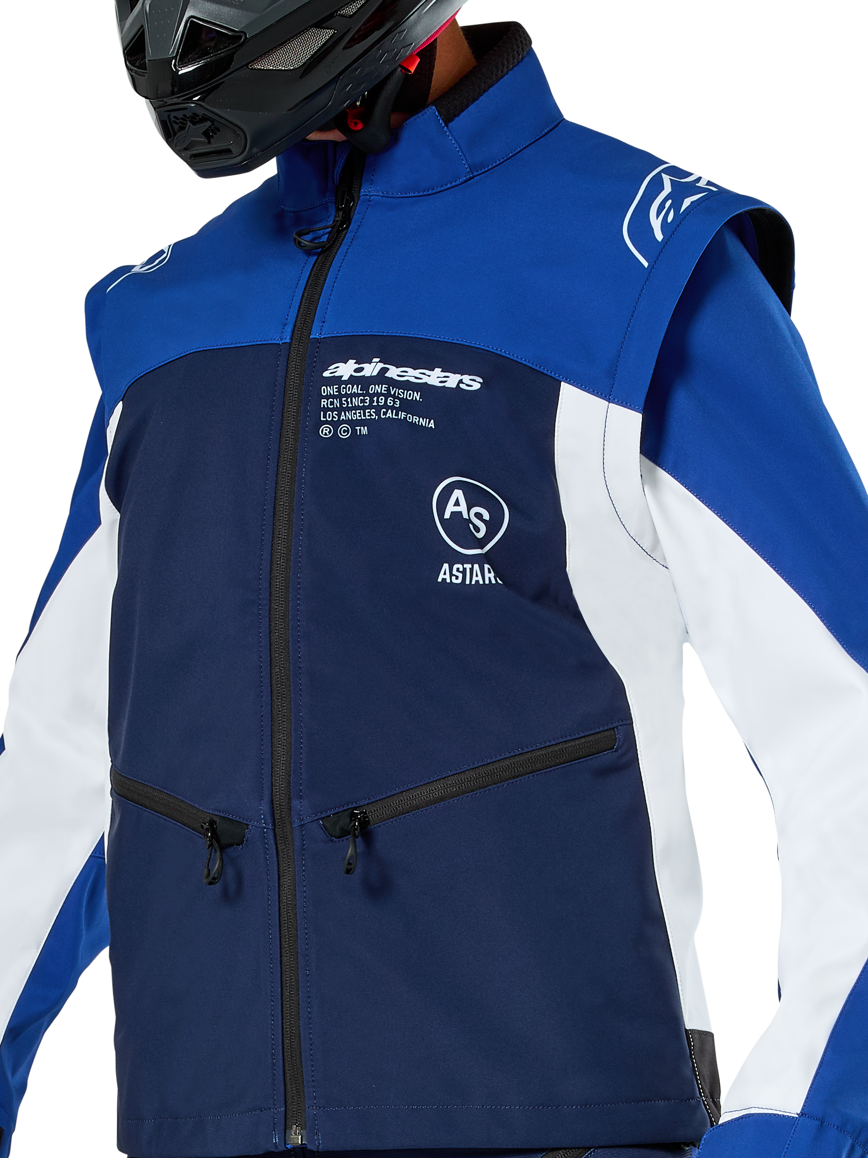 Chaqueta Softshell Alpinestars Lite-Dura, chaqueta de motocross y enduro, azul marino, azul brillante y blanco, con logotipos de Alpinestars en blanco en el pecho y bolsillos con cremallera, usada con un casco negro, construcción de softshell duradera con mangas desmontables para conducción off-road