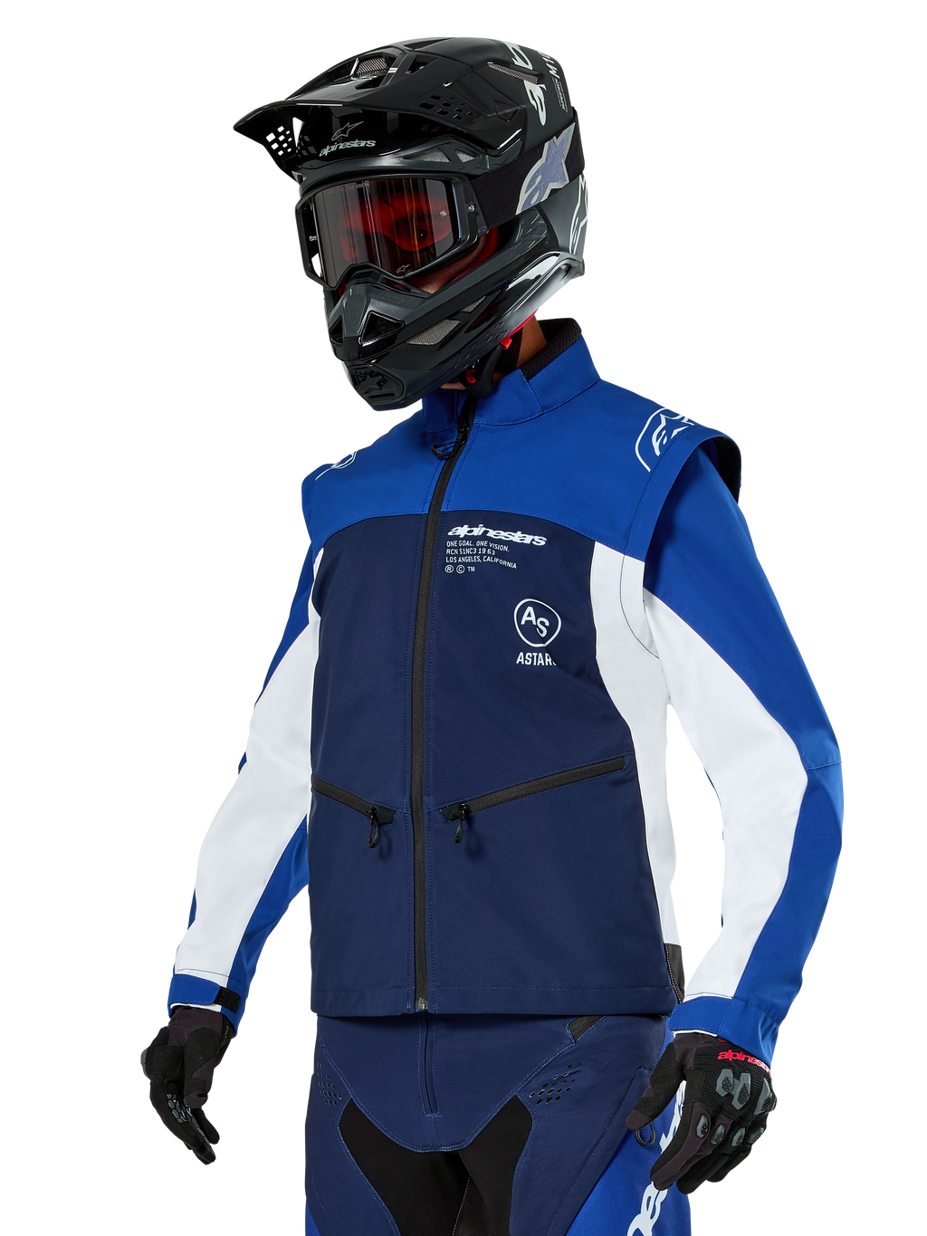Chaqueta Alpinestars Lite-Dura Softshell, azul marino, azul brillante y blanco, chaqueta para enduro off-road, usada con casco negro y gafas de tinte rojo, diseño deportivo de bloques de color con múltiples cremalleras y logotipos de la marca, textil resistente para motocross y conducción por senderos