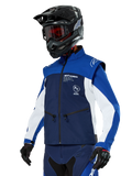 Chaqueta Alpinestars Lite-Dura Softshell, azul marino, azul brillante y blanco, chaqueta para enduro off-road, usada con casco negro y gafas de tinte rojo, diseño deportivo de bloques de color con múltiples cremalleras y logotipos de la marca, textil resistente para motocross y conducción por senderos