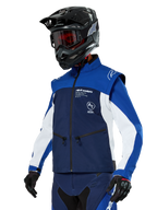 Chaqueta Alpinestars Lite-Dura Softshell, azul marino, azul brillante y blanco, chaqueta para enduro off-road, usada con casco negro y gafas de tinte rojo, diseño deportivo de bloques de color con múltiples cremalleras y logotipos de la marca, textil resistente para motocross y conducción por senderos