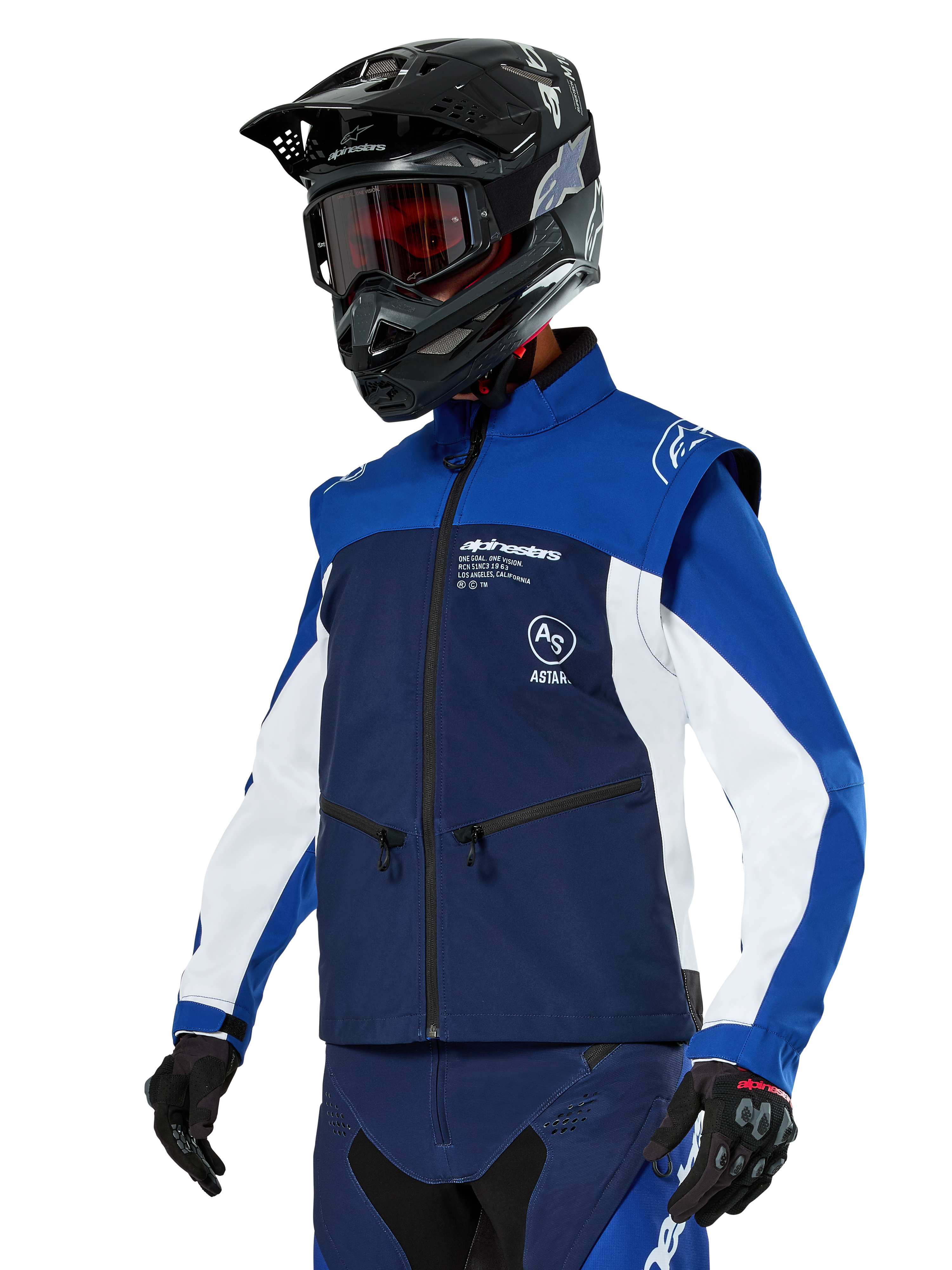 Chaqueta Alpinestars Lite-Dura Softshell, azul marino, azul brillante y blanco, chaqueta para enduro off-road, usada con casco negro y gafas de tinte rojo, diseño deportivo de bloques de color con múltiples cremalleras y logotipos de la marca, textil resistente para motocross y conducción por senderos