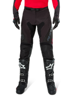 Pantalones Alpinestars Pro-Dura, pantalones de enduro en color negro y magnet, combinados con un jersey rojo de manga larga y botas de motocross negras, con logotipos grises de Alpinestars y una construcción de ripstop resistente para conducción off-road.