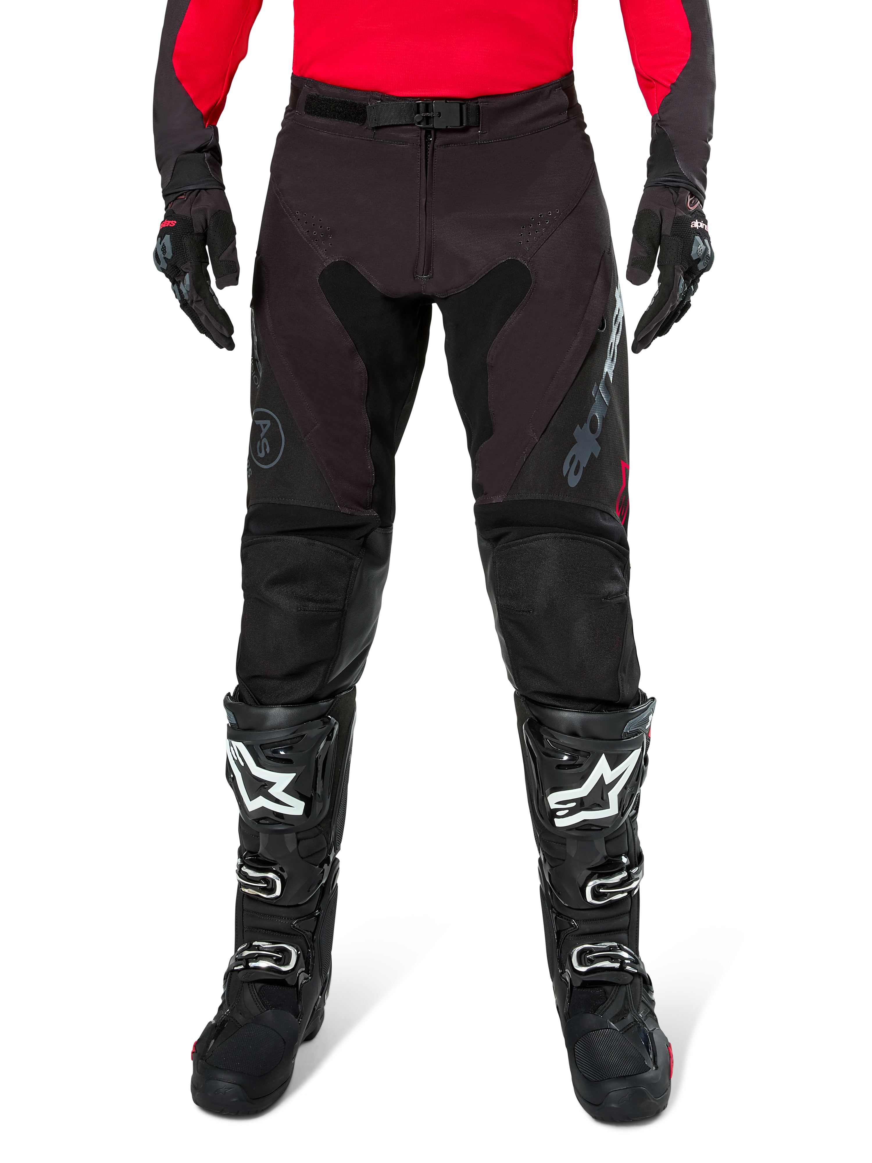 Pantalones Alpinestars Pro-Dura, pantalones de enduro en color negro y magnet, combinados con un jersey rojo de manga larga y botas de motocross negras, con logotipos grises de Alpinestars y una construcción de ripstop resistente para conducción off-road.