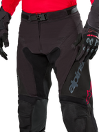 Alpinestars Pro-Dura Pants, pantalones de enduro, color negro magnet white con detalles rojos, cierre de hebilla magnética y bragueta con cremallera, usados con jersey rojo y guantes negros, construcción de ripstop duradera para conducción off-road