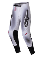 Alpinestars 2025 Supertech Maker Pants, pantalones de motocross, color plata y negro, con grandes logotipos Astars negros en los muslos, marca técnica roja en la cadera, paneles interiores de cuero negro en las rodillas y zonas de ventilación perforadas