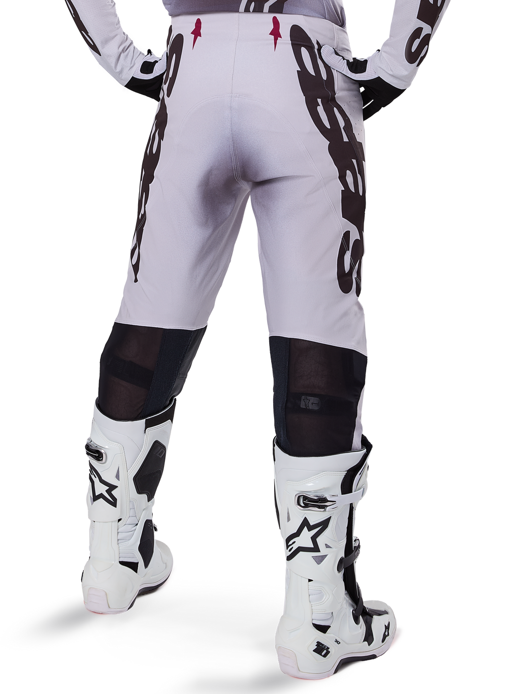 Alpinestars 2025 Supertech Maker Pants, pantalones de motocross, plateado y negro, vista trasera con grandes logotipos negros en los muslos y zonas de malla transpirable detrás de las rodillas, usados con botas Alpinestars blancas
