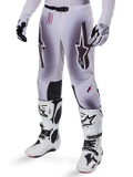 Pantalones Alpinestars Supertech Maker 2025, pantalones de motocross, en color plata y negro, con logotipos de estrellas grandes y letras rojas, mostrados con botas y guantes blancos a juego