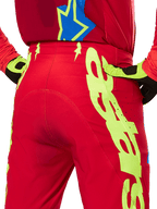 Alpinestars 2025 Supertech Maker Pants, Motocross Pants, Bright Red and Yellow Fluo, rear view featuring large yellow graphics on the legs and matching fluo yellow and black gloves, professional off-road racing gear