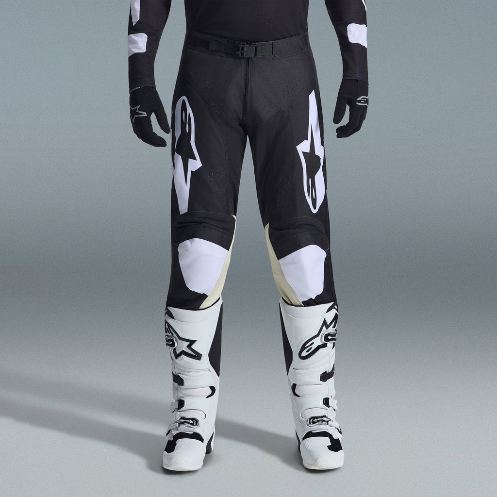 Alpinestars 2026 Racer Air Riway Gear Set, pantalones de motocross negros y blancos con paneles interiores de las rodillas en color arena, combinados con botas de carreras blancas y guantes negros, equipamiento ligero y ventilado para competición off-road