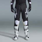 Alpinestars 2026 Racer Air Riway Gear Set, pantalones de motocross negros y blancos con paneles interiores de las rodillas en color arena, combinados con botas de carreras blancas y guantes negros, equipamiento ligero y ventilado para competición off-road