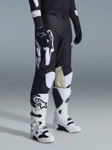 Pantalones Alpinestars Racer Air Riway 2026, pantalones de motocross negros y blancos, usados con botas Tech Series blancas y negras y jersey negro de manga larga, con logotipos Alpinestars en blanco, perforaciones cortadas con láser y paneles interiores de la rodilla en cuero de cabra color canela para rendimiento off-road.