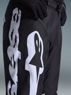 Alpinestars 2026 Racer Air Riway Pants, pantalones de motocross, blanco y negro, vista de primer plano con la marca Alpinestars en blanco, perforaciones láser para el flujo de aire y hebilla de cintura ajustable, tejido duradero para conducción off-road