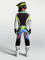 Pantalones Supertech Dyna de Alpinestars, lila claro y verde flúor, vista trasera de piloto con equipo de motocross completo