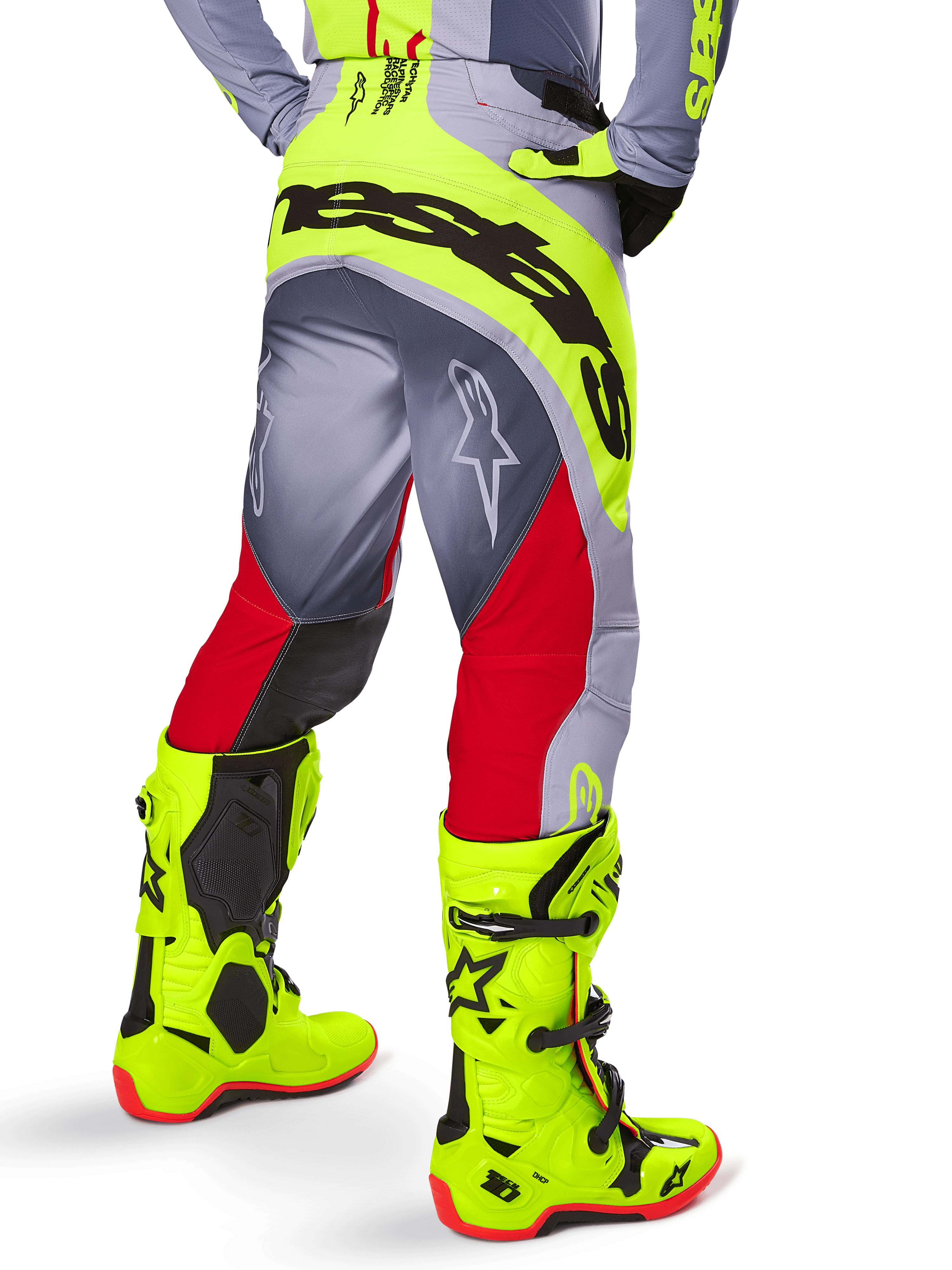 Alpinestars Techstar Melt Pants 2025, pantalones de motocross, rojo brillante y gris con detalles en amarillo neón, vista trasera que destaca el logotipo negro en el asiento, usados con botas amarillo neón y jersey gris, ajuste atlético de competición para off-road.