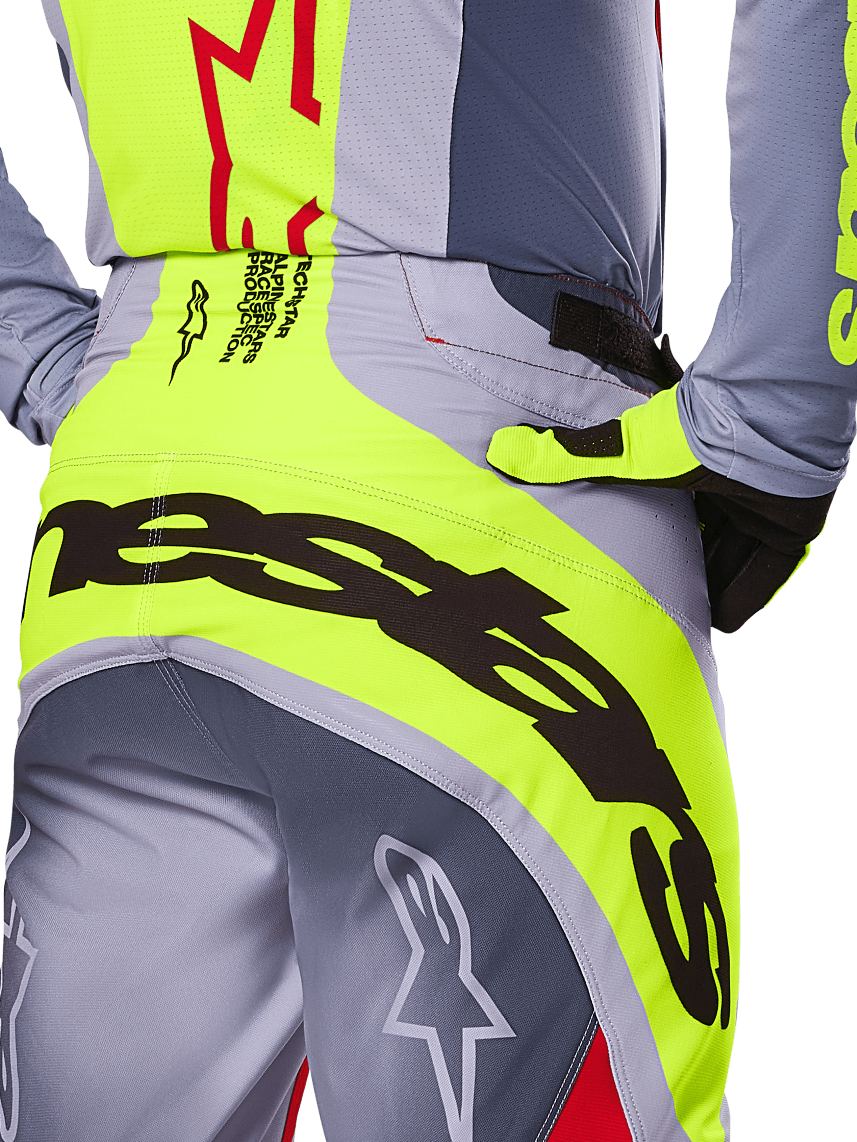 Pantalones Alpinestars 2025 Techstar Melt, primer plano de la zona trasera y la cintura, diseño en gris y amarillo neón con logotipos negros grandes, detalles de estrellas y texto técnico, equipamiento de motocross de alto rendimiento