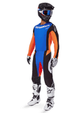 Alpinestars 2025 Techstar Melt Gear Set, piloto de motocross con jersey azul y mangas naranjas, pantalones negros con detalles azules y naranjas, casco negro a juego con gafas azules, y botas de carreras blancas y negras