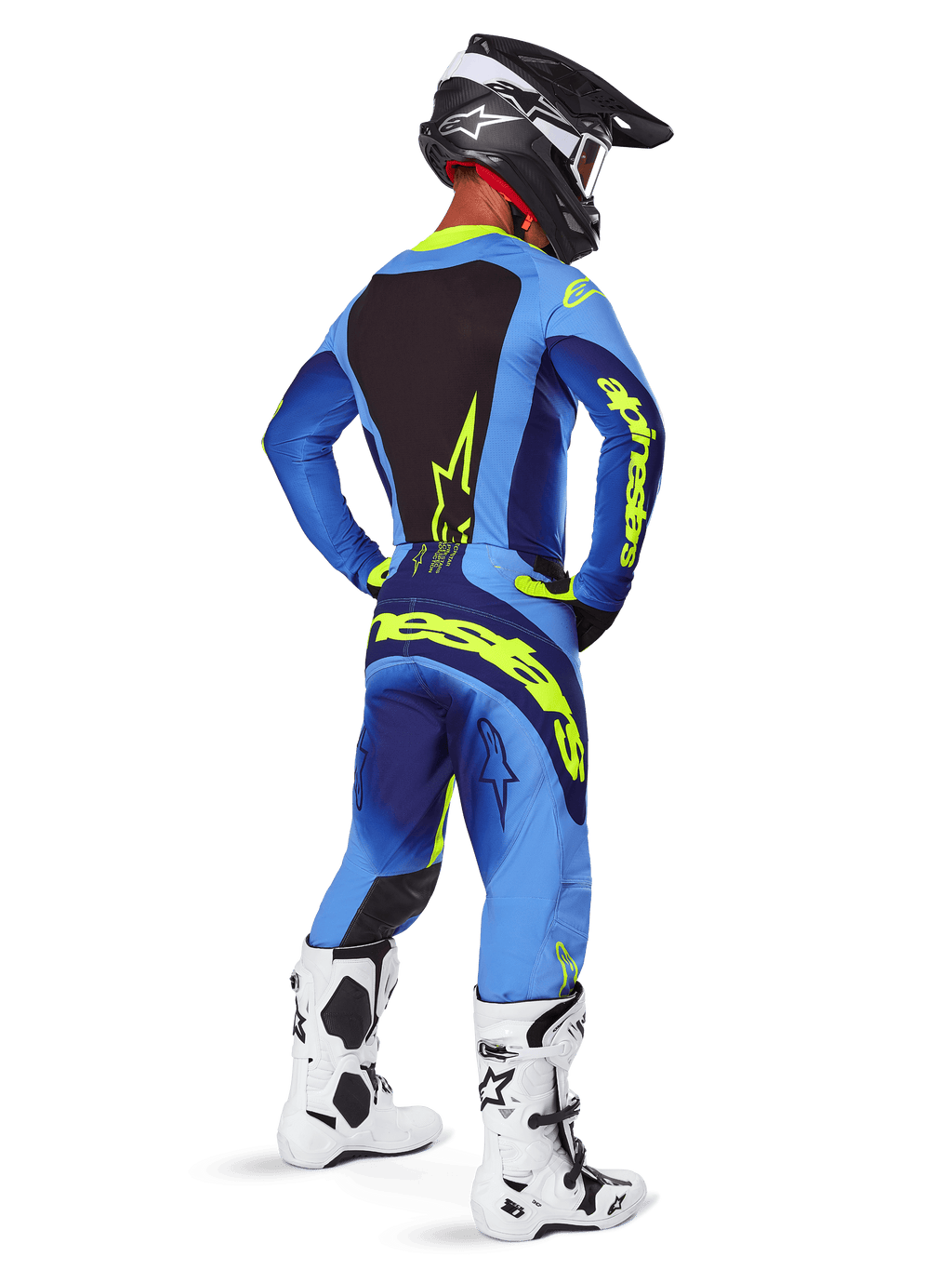 Pantalones Alpinestars 2025 Techstar Melt, equipamiento de motocross, amarillo flúor y azul, vista trasera de un piloto con jersey azul a juego y grandes logotipos amarillos, botas blancas y negras, y casco negro, conjunto de carreras coordinado para rendimiento todoterreno