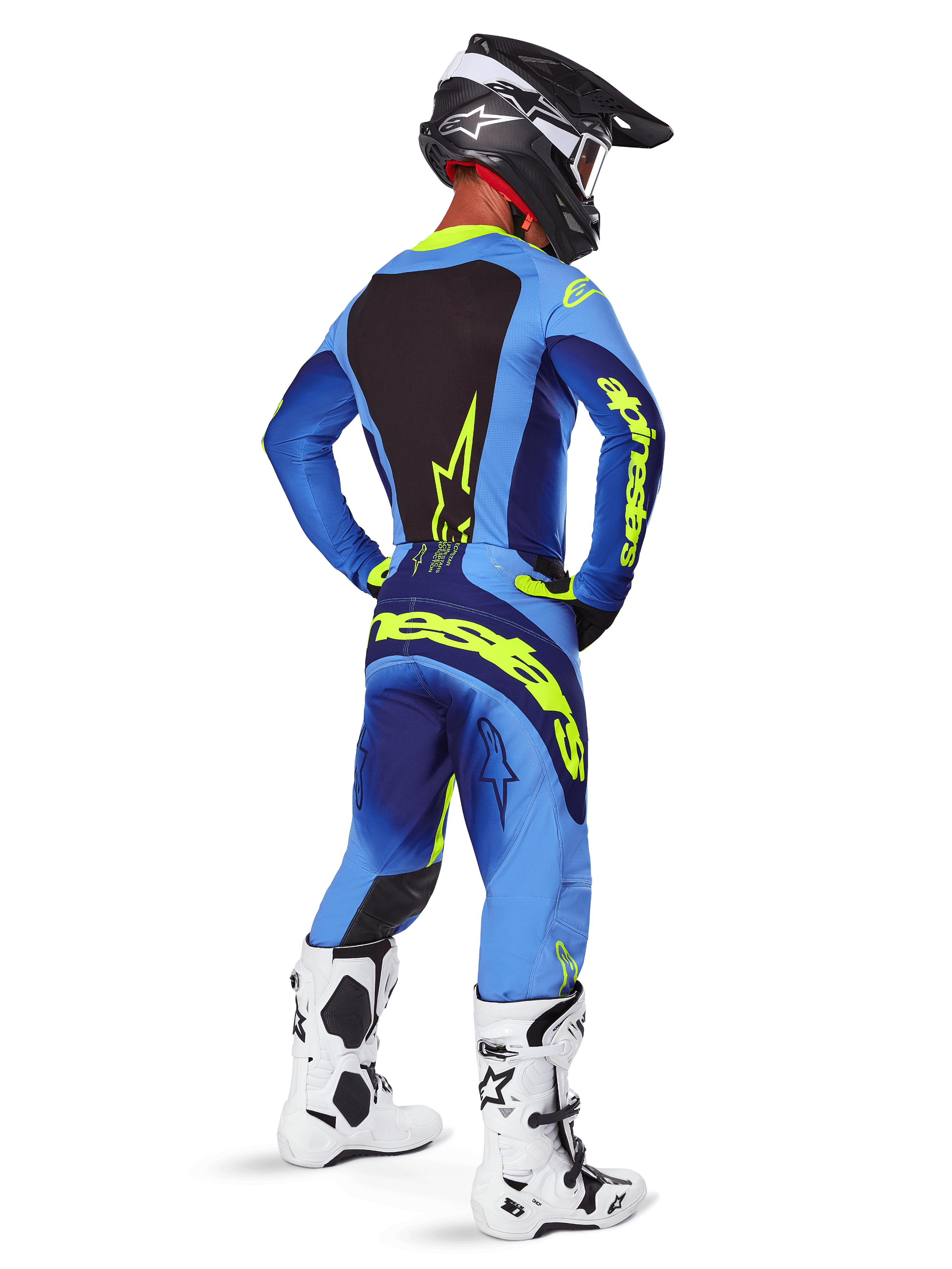 Pantalones Alpinestars 2025 Techstar Melt, equipamiento de motocross, amarillo flúor y azul, vista trasera de un piloto con jersey azul a juego y grandes logotipos amarillos, botas blancas y negras, y casco negro, conjunto de carreras coordinado para rendimiento todoterreno
