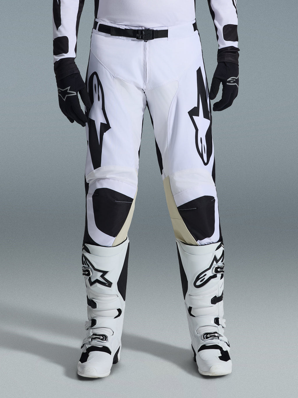 Alpinestars 2026 Racer Riway Pants, pantalones de motocross, blanco y negro, combinados con botas de motocross blancas y negras a juego y guantes negros, con el logotipo de Alpinestars en negro en los muslos, diseño técnico para rendimiento off-road.
