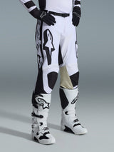 Pantalones Alpinestars 2026 Racer Riway, pantalones de motocross, blancos y negros, con gráficos y logotipos llamativos de Alpinestars en negro, refuerzos interiores de cuero en color arena en las rodillas, combinados con botas de motocross blancas y negras y guantes negros, equipo de carreras profesional para conducción off-road