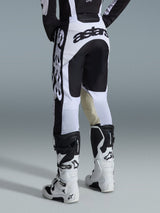 Pantalones Alpinestars Racer Riway 2026, pantalones de motocross, blancos y negros, vista trasera que muestra la marca en negro llamativo en el asiento y los laterales, paneles internos de las rodillas en cuero de cabra color canela, combinados con botas de motocross a juego en blanco y negro