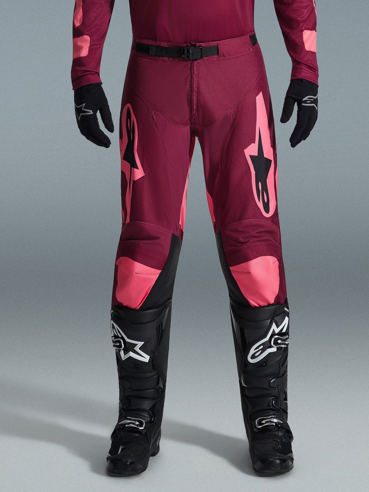 Alpinestars 2026 Racer Riway Pants, pantalones de motocross, rojo oscuro y rosa, con logos de estrella, diseño ajustado con cinturón negro, acabado brillante