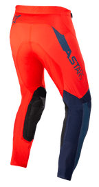 Pantalones Alpinestars Supertech Blaze, pantalones de motocross, rojo brillante y azul oscuro, vista trasera de tres cuartos, con el logotipo ASTARS en azul oscuro en el lateral, paneles de rodilla reforzados en negro y ajuste atlético para un rendimiento todoterreno