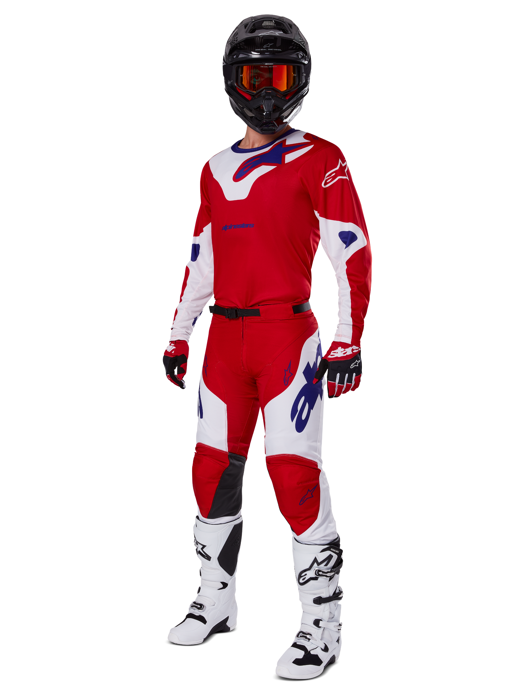 Alpinestars 2025 Racer Veil Pants, pantalones de motocross, rojo brillante y blanco, usados como parte de un conjunto completo de equipamiento de competición que incluye una camiseta roja y blanca a juego, casco negro con gafas naranjas, botas blancas y guantes rojos, con logotipos de Alpinestars en un llamativo color azul.