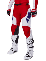 Pantalones Alpinestars 2025 Racer Veil, pantalones de motocross, rojo brillante y blanco, con logotipos de Alpinestars azules y paneles internos de cuero negro en las rodillas, combinados con guantes rojos a juego y botas de motocross blancas, conjunto de equipamiento coordinado para carreras todoterreno