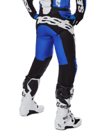 Alpinestars Racer Veil Pants 2025, pantalones de motocross, azul y negro, vista trasera que muestra un gran logotipo blanco en el asiento, usados con jersey a juego y botas blancas, material técnico duradero para conducción todoterreno