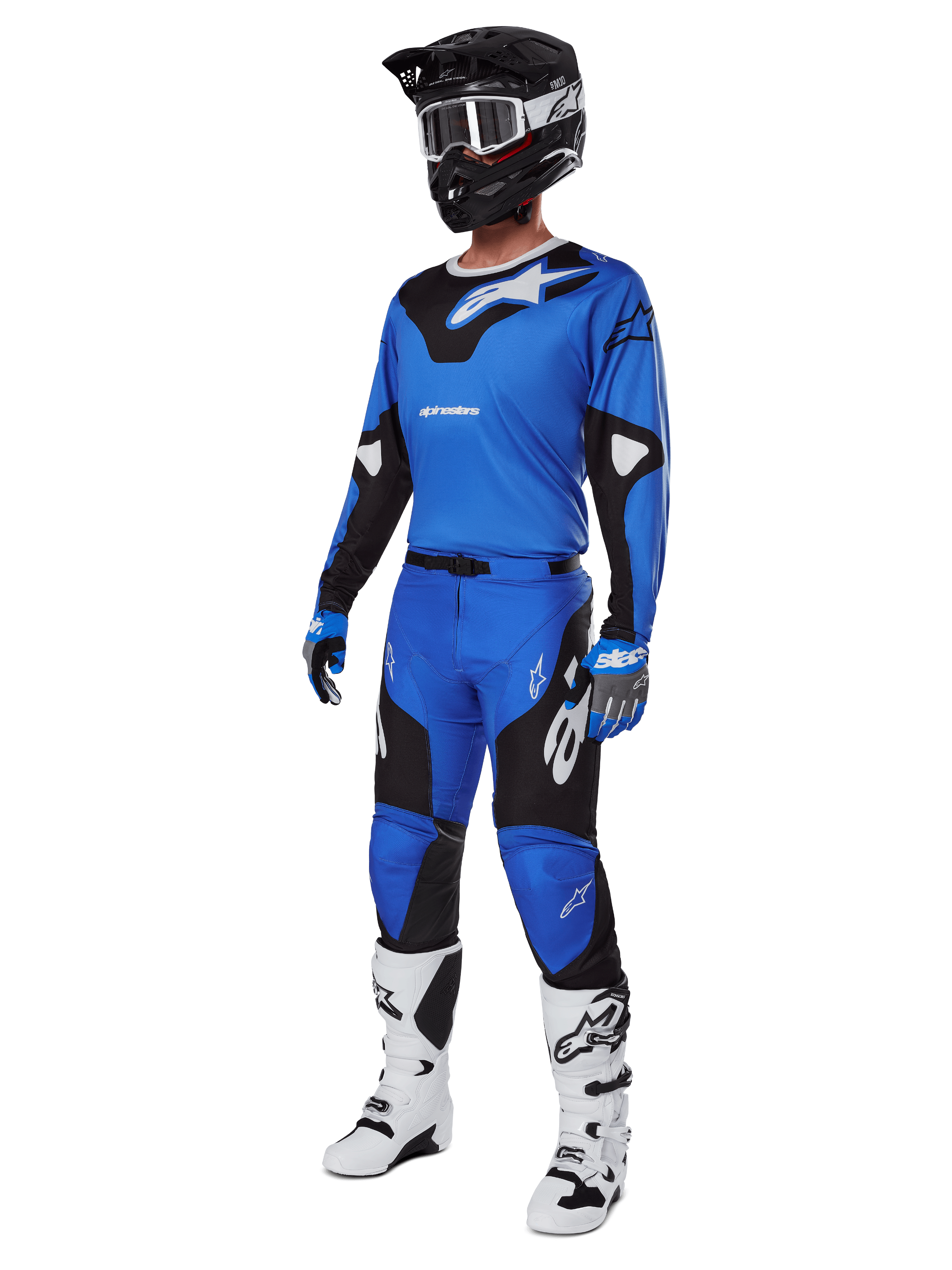 Piloto de motocross con equipamiento completo de competición, que incluye los pantalones Alpinestars 2025 Racer Veil en azul y negro, jersey azul a juego con detalles blancos, casco negro con gafas blancas, botas blancas y negras, y guantes azules, conjunto coordinado para carreras off-road