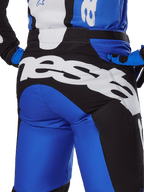 Alpinestars 2025 Racer Veil Pants, pantalones de motocross, azul y negro, primer plano de la parte trasera con un gran logotipo de Alpinestars en blanco sobre el panel del asiento negro, combinados con equipamiento azul y negro a juego para un look off-road coordinado