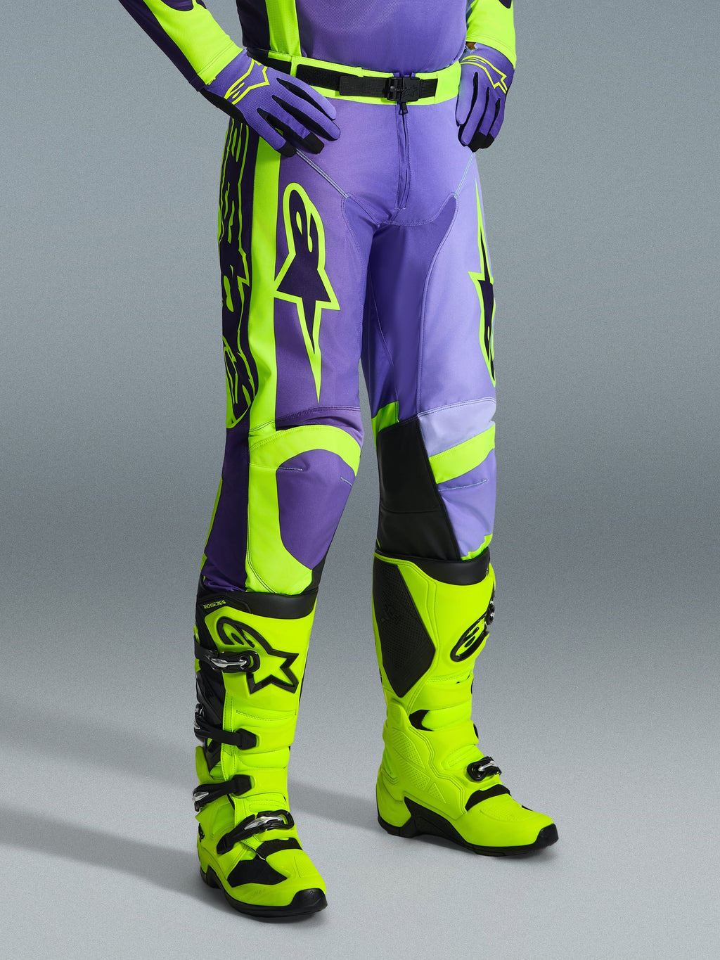 Pantalones Alpinestars 2026 Racer Portl, pantalones de motocross en morado y amarillo flúor, usados por un piloto con botas amarillo flúor y guantes morados a juego, con el logotipo de Alpinestars y un diseño ergonómico para rendimiento off-road