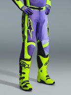 Pantalones Alpinestars 2026 Racer Portl, pantalones de motocross en morado y amarillo flúor, usados por un piloto con botas amarillo flúor y guantes morados a juego, con el logotipo de Alpinestars y un diseño ergonómico para rendimiento off-road