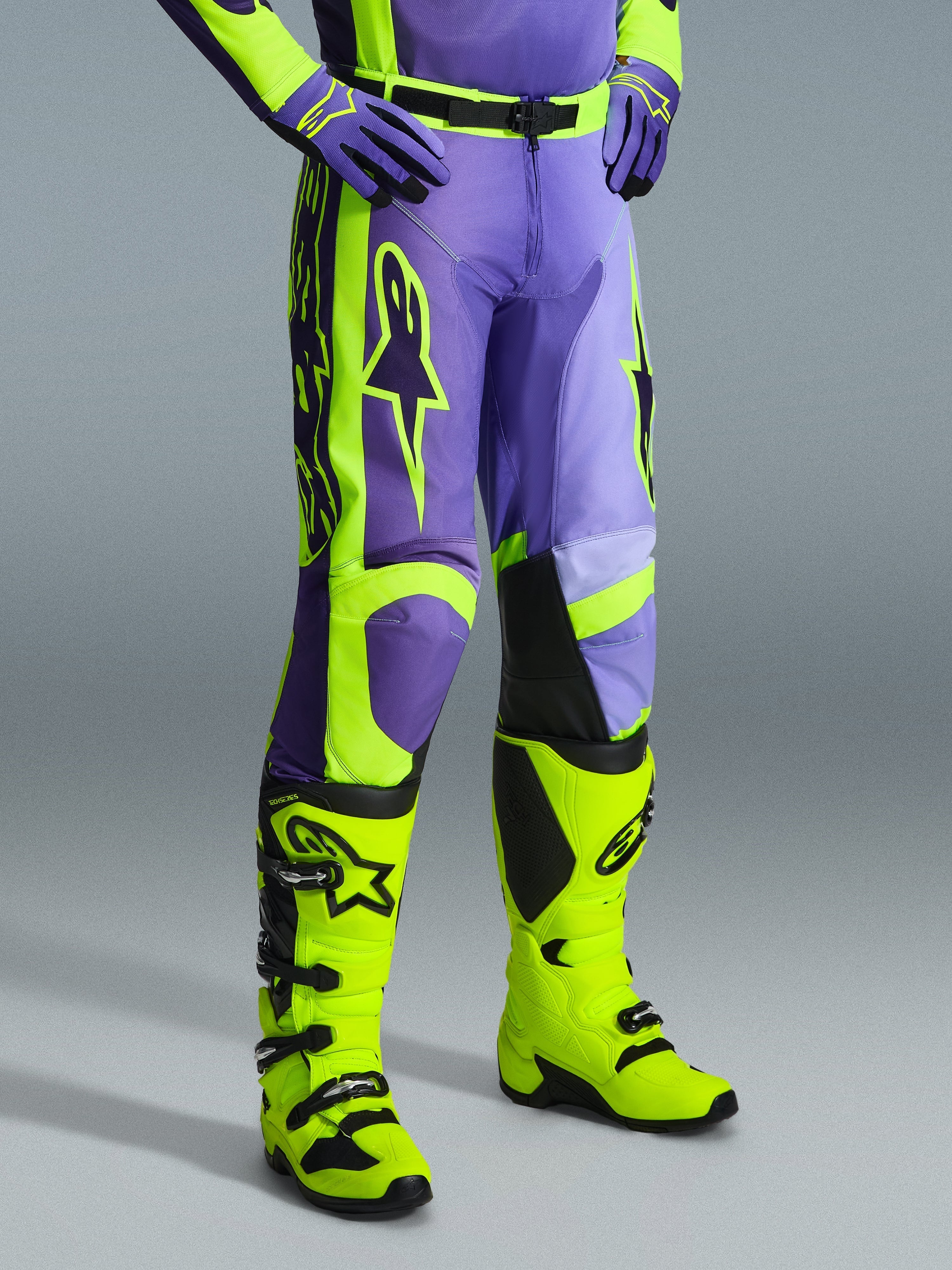 Pantalones Alpinestars 2026 Racer Portl, pantalones de motocross en morado y amarillo flúor, usados por un piloto con botas amarillo flúor y guantes morados a juego, con el logotipo de Alpinestars y un diseño ergonómico para rendimiento off-road