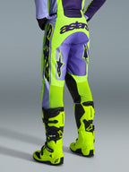 Alpinestars 2026 Racer Portl Pants, pantalones de motocross, púrpura y amarillo flúor, vista trasera con logotipo astars llamativo y detalles en púrpura, usados con botas de motocross amarillo flúor a juego, material sintético duradero para carreras off-road