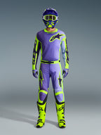Alpinestars 2026 Racer Portl Pants y conjunto de equipación a juego, piloto de motocross en púrpura y amarillo flúor, con jersey, casco, gafas coordinadas y botas de color amarillo brillante, diseñado para el rendimiento off-road