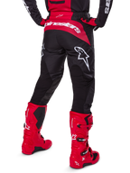 Alpinestars 2025 Fluid Haul Gear Set, Rear View, Black and Red motocross pants with large white logos, matching jersey, and vibrant red Tech 7 boots, coordinated off-road racing kit