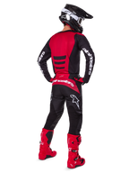 Motocross rider wearing the Alpinestars 2025 Fluid Haul Gear Set from a rear view, Red and Black jersey with white branding, matching black pants with red accents, bright red boots and black helmet with white goggles, complete coordinated outfit for off-road racing