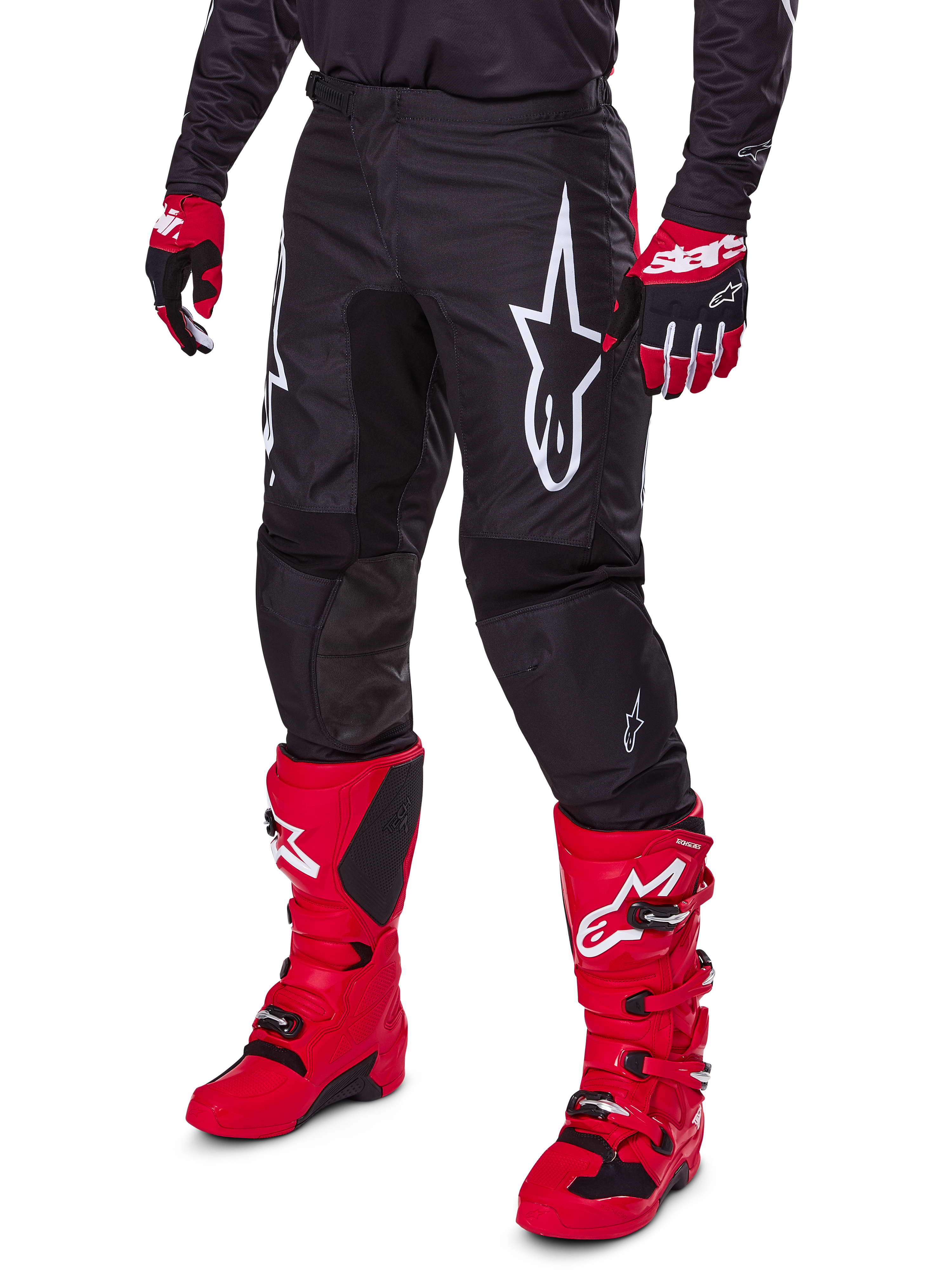 Alpinestars 2025 Fluid Haul Pants, Motocross Pants, Black, featuring a large white Alpinestars logo, worn with bright red boots and red and black gloves, durable 600D polyfabric construction with ergonomic cut for off-road racing