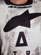 Alpinestars 2026 Racer Lahnd Jersey, primer plano de la zona del pecho, patrón Sand Camo con gran logotipo de estrella negra y marca Alpinestars, polifabricado técnico transpirable para conducción off-road