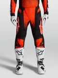 Alpinestars Techstar Swan 2027, pantalones de motocross en rojo cardenal y negro, con botas y guantes blancos para off-road.